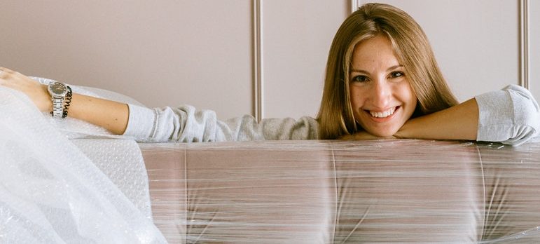 A woman smiling behind the wrapped couch