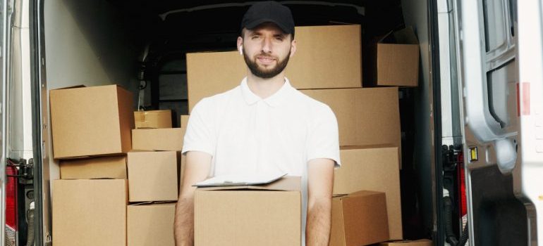 man in a white shirt carrying cardboard moving boxes