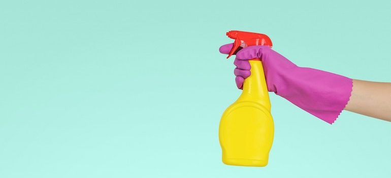 hand wearing a glove holding a cleaning product