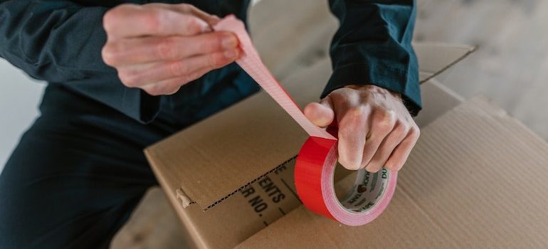 A man holding a duct tape in front of a box