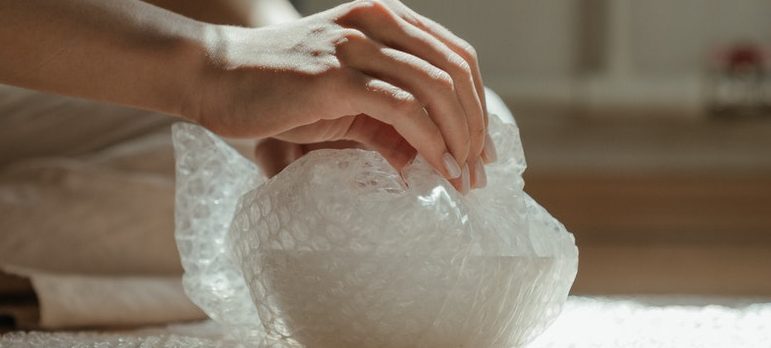 woman packing fragile item in a bubble wrap