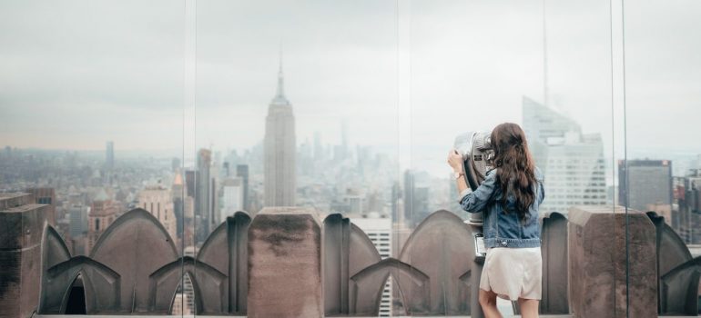 a woman looking at the New York skyline from a tall building