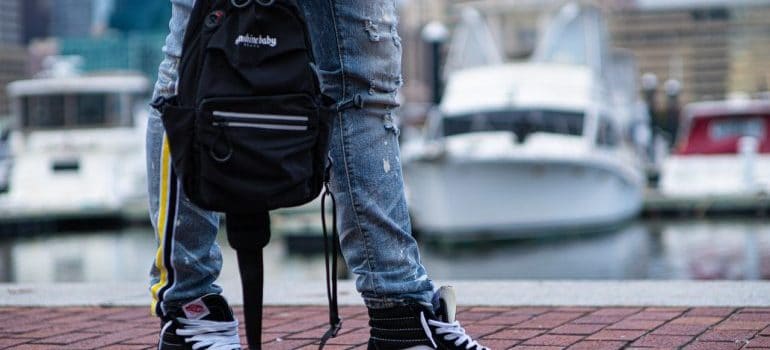 Person holding a backpack in sneakers